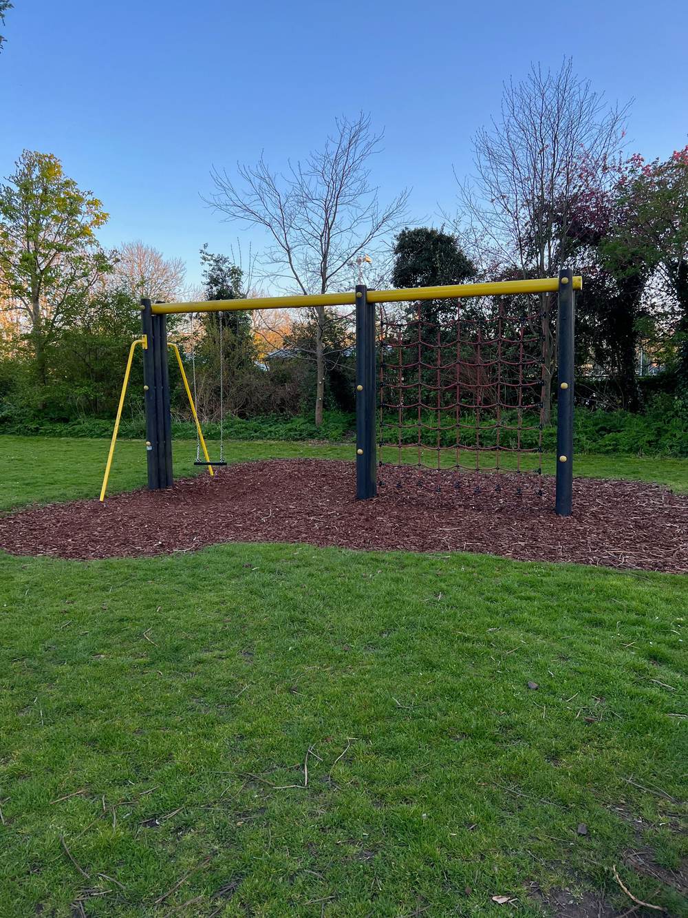 Swing and climbing net over bark surfacing